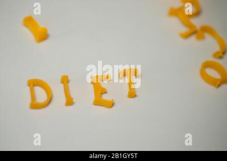 WORTDIÄT besteht aus essbaren Buchstaben. Nudeldiät Lebensmittel. Pasta in Form von Buchstaben auf grauem Hintergrund. Richtiges Ernährungskonzept. Kopierbereich Stockfoto