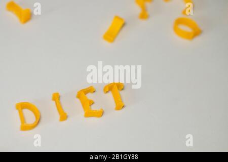 WORTDIÄT besteht aus essbaren Buchstaben. Nudeldiät Lebensmittel. Pasta in Form von Buchstaben auf grauem Hintergrund. Richtiges Ernährungskonzept. Kopierbereich Stockfoto