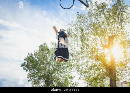 Basketballsportler machen auf dem Platz im urbanen Grunge Camp mit Rückenlicht einen riesigen Slam Dunk - Junger Mann in Aktion bei Sonnenuntergang - Sportkonzept - Wa Stockfoto