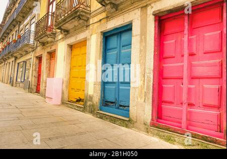 Farbenfrohe, abgenutzte, bemalte Türen entlang der Straße in Porto - Künstlerisches konzept der portugiesischen Stadt - Warmer gefilterter Look Stockfoto
