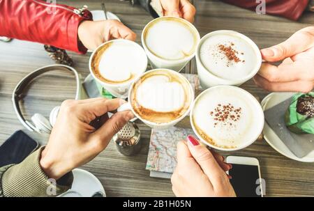 Freundesgruppe zum Toasten von Cappuccino und Milch mit Kakao - Nahaufnahme von jungen Leuten, die im Restaurant der Café-Bar trinken - Frühstück und geselliger Mitstreiter Stockfoto