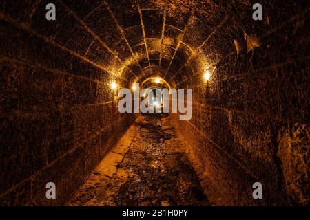 Dunkel und cremefarben alter historischer Gewölbeüberschwemmungstunnel im Untergrund. Stockfoto