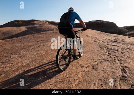 25. Februar 2020: Das Bureau of Land Management kündigte am 24. Februar an, zwei Parzellen innerhalb des Sand Flats Special Recreation Area in der Nähe von Moab, Utah, aus einem bevorstehenden Verkauf von Öl- und Gaspacht zu entfernen. Der Plan hätte Sondierungsbohrungen unter dem Slickrock Trail ermöglicht, einem der beliebtesten Mountainbike-Ziele der Welt. Bild: 5. April 2015 - Moab, Utah, USA - Mountain Biker TIM-SPUR, die den roten Sandstein des berühmten Slickrock-Trails mit Colorado River und Canyons hinter sich führt. Der Slickrock Trail ist ein beliebtes Mountainbike-Ziel mit weltweitem Ruhm. T Stockfoto