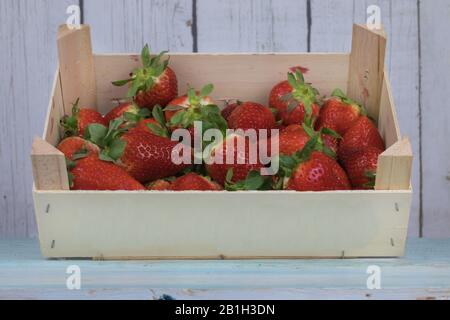 Erdbeeren in einer Holzkiste isoliert auf hellem Holzhintergrund Stockfoto