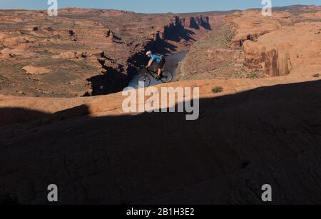 25. Februar 2020: Das Bureau of Land Management kündigte am 24. Februar an, zwei Parzellen innerhalb des Sand Flats Special Recreation Area in der Nähe von Moab, Utah, aus einem bevorstehenden Verkauf von Öl- und Gaspacht zu entfernen. Der Plan hätte Sondierungsbohrungen unter dem Slickrock Trail ermöglicht, einem der beliebtesten Mountainbike-Ziele der Welt. Bild: 5. April 2015 - Moab, Utah, USA - Mountain Biker TIM-SPUR, die den roten Sandstein des berühmten Slickrock-Trails mit Colorado River und Canyons hinter sich führt. Der Slickrock Trail ist ein beliebtes Mountainbike-Ziel mit weltweitem Ruhm. T Stockfoto