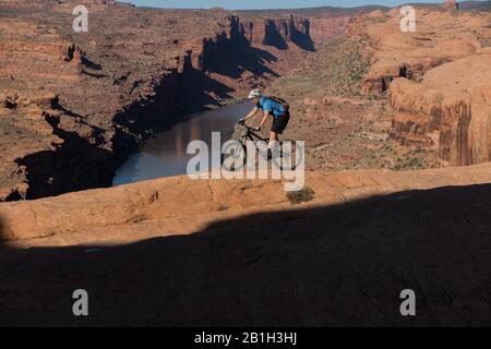 25. Februar 2020: Das Bureau of Land Management kündigte am 24. Februar an, zwei Parzellen innerhalb des Sand Flats Special Recreation Area in der Nähe von Moab, Utah, aus einem bevorstehenden Verkauf von Öl- und Gaspacht zu entfernen. Der Plan hätte Sondierungsbohrungen unter dem Slickrock Trail ermöglicht, einem der beliebtesten Mountainbike-Ziele der Welt. Bild: 5. April 2015 - Moab, Utah, USA - Mountain Biker TIM-SPUR, die den roten Sandstein des berühmten Slickrock-Trails mit Colorado River und Canyons hinter sich führt. Der Slickrock Trail ist ein beliebtes Mountainbike-Ziel mit weltweitem Ruhm. T Stockfoto