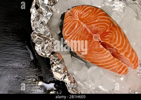 Horizontal platziertes Lachssteak auf Aluminiumfolie mit Eis. Stockfoto