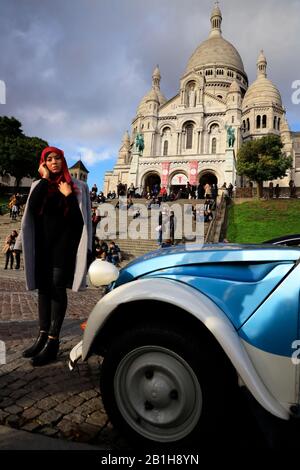 Basilika Sacré-Coeur in Montmartre.Basilique du Sacré Cœur de Montmartre mit einer weiblichen Touristen posiert von einem alten Citroen Auto im Vordergrund.Paris. Stockfoto