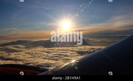 Blick auf den Gipfel des Mount Kinabalu, Sabah, Malaysia, umgeben von Wolken, mit der aufgehenden Sonne direkt über seinem Gipfel. Aus dem Fenster einer PLA übernommen Stockfoto