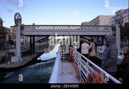 Ein Ausflugsboot, das unter Der Hubbrücke und der Fußgängerbrücke an der Rue de Crimee über Bassin de la Villette.Paris.France führt Stockfoto