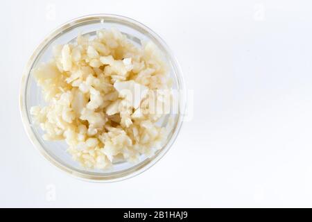 Zerdrückter Knoblauch in der Glasschale. Healthy Food Concept Top View auf weißem Hintergrund Stockfoto