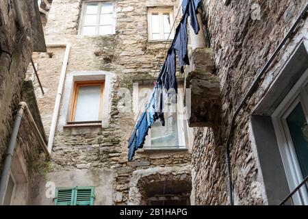 Im mittelalterlichen Steindorf Dolceacqua, Italien, hängt eine Auswahl blauer Kleidung an einer Wäscheleine. Stockfoto