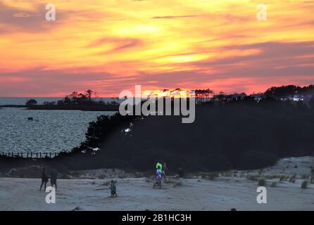 Menschen, die auf dem Sand laufen, während die Sonne über Albemarle Sound im JockeyÕs Ridge State Park untergeht, dem höchsten Stockfoto