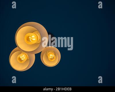 Drei runde, moderne Deckenleuchten hängen von der Decke aus der Unteransicht im dunklen Raum mit Kopienfläche. Stockfoto
