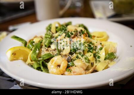 Meeresfrüchte alfredo in cremiger Soße mit Garnelen, Jakobsmuscheln und Pilzen, sautiert mit Spinat und Eierfettuccinnudeln. Stockfoto