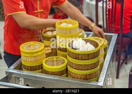 Kellnerin in chinesischer Tracht, die Dimmsum in Bambusdampfern serviert Stockfoto