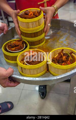 Chinesische Kellnerin, die Stewed Chicken Feet im Dimsum Restaurant serviert Stockfoto