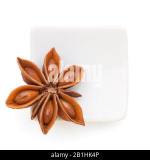 Anisstern (Illicium verum) in einer weißen Schüssel auf weißem Grund. Auch als Star Anis oder Chinese Star Anis bezeichnet. Stockfoto