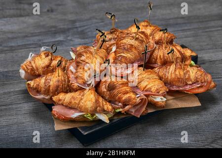 Ein großer Satz von Croissants mit verschiedenen Füllungen, die auf einem Tisch auf grauem Hintergrund aufgestellt sind. Seth fast Food. Grauer Hintergrund, Kopierbereich Stockfoto