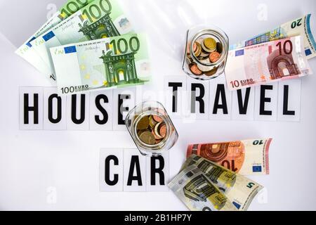 Euro im Glasbecher mit Münzen, Sparkonzept, Wörter Haus, Reise und Autotext auf weißem Hintergrund Stockfoto