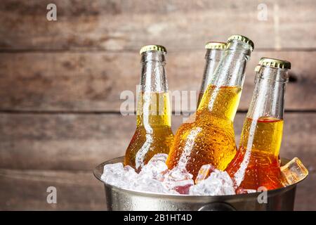 Kalte Flaschen Bier im Eimer auf dem Holzhintergrund Stockfoto