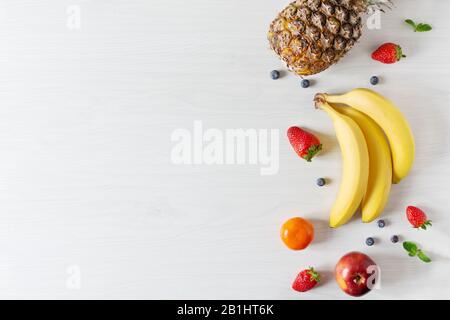 Kreative Komposition verschiedener Obst- und Gemüsesorten auf weißem Holztisch - Hintergrund Draufsicht. Kopierbereich. Gesundes Esskonzept. Entgiftung. Stockfoto