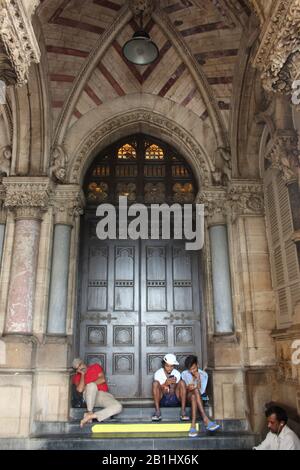 September 2019 In Mumbai, Maharashtra, Indien. Leute, die Chhatrapati Shivaji Maharaj Terminus oder Victoria Terminus Bahnhof sitzen Stockfoto