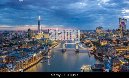 Luftbild der Tower Bridge London bei Nacht. Drohnenfoto von der Themse, einschließlich Shard, Gherkin und Rathaus Stockfoto