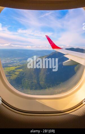 Luftbild aus dem Flugzeugfenster, dem grünen Tal der Schweiz, den Bergen und dem Flügel Stockfoto
