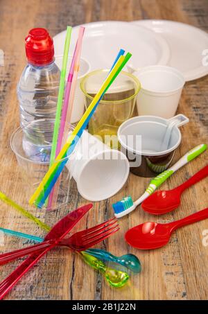 Plastikmüll, verschiedene Plastikutensilien, Umweltschutz auf Holzhintergrund Stockfoto