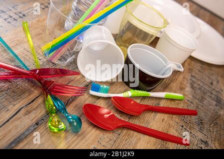 Plastikmüll, verschiedene Plastikutensilien, Umweltschutz auf Holzhintergrund Stockfoto