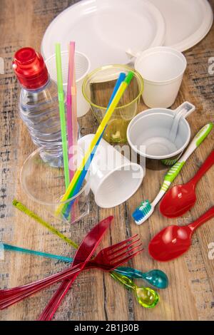 Plastikmüll, verschiedene Plastikutensilien, Umweltschutz auf Holzhintergrund Stockfoto