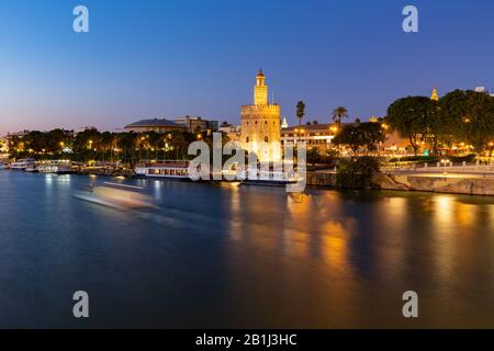 Torre del Oro nachts am Fluss Guadalquivir in Sevilla, Andalucia, Spanien. Stockfoto