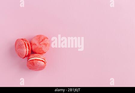 Schmackhafte französische Makronen auf pinkfarbenem Hintergrund. Flaches Lay. Platz für Text. Stockfoto