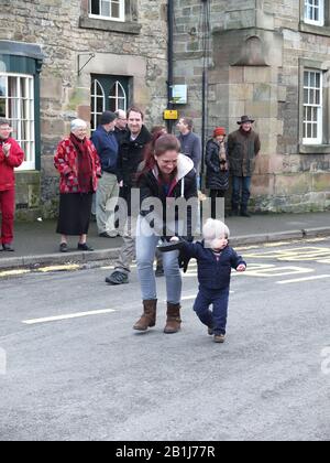 Mutter- und Kleinkindrennen mit Pfannen und Pfannkuchen während Winster Pancake-Rennen Shrove Tuesday Pancake Day Derbyshire UK Stockfoto