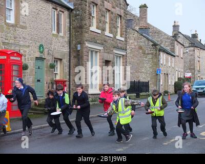 Schüler mit Pfannen und Pfannkuchen am Start eines Rennens während Winster Pancake-Rennen Shrove Tuesday Pancake Day Derbyshire UK Stockfoto