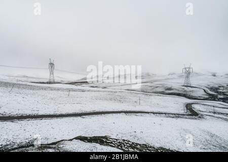 Elektrizitätspylon auf dem Berg, der mit Schnee bedeckt ist Stockfoto