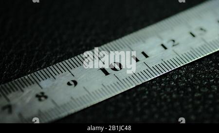 Metalllineal auf schwarzem Hintergrund mit einer klaren Zahl 10 Stockfoto