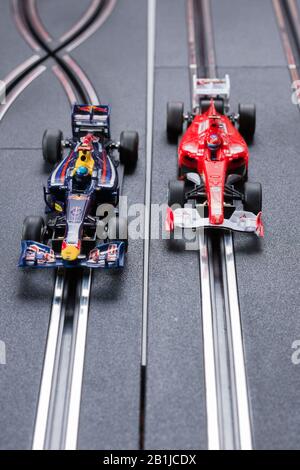 Modell Formel 1 Redbull und ein Ferrari Style Slot Cars, die auf einer Scalextric-Strecke Rennen Stockfoto