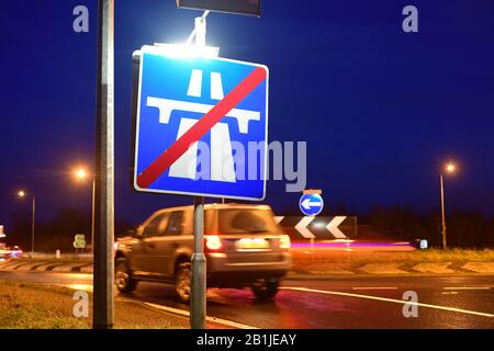Verkehr, der am Ende des Autobahnwarnschildes an der Kreuzung im Zwielicht leeds yorkshire united Kingdom vorbeiführt Stockfoto