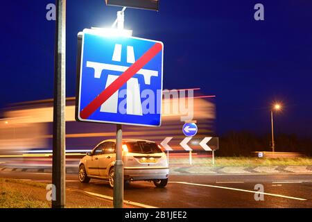 Verkehr, der am Ende des Autobahnwarnschildes an der Kreuzung im Zwielicht leeds yorkshire united Kingdom vorbeiführt Stockfoto