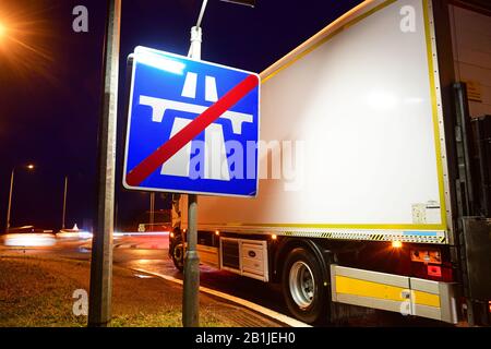 LKW, der am Ende des Autobahnwarnschildes an der Kreuzung im Zwielicht leeds yorkshire united Kingdom vorbeiführt Stockfoto