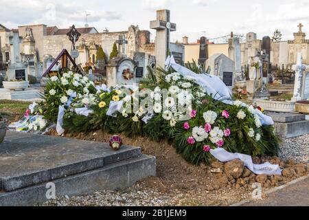 Frisches Grabmal mit Grabkränzen und Blumen auf dem Friedhof, Sopron, Ungarn Stockfoto