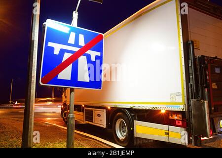 LKW, der am Ende des Autobahnwarnschildes an der Kreuzung im Zwielicht leeds yorkshire united Kingdom vorbeiführt Stockfoto