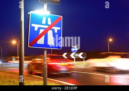 Verkehr, der am Ende des Autobahnwarnschildes an der Kreuzung im Zwielicht leeds yorkshire united Kingdom vorbeiführt Stockfoto
