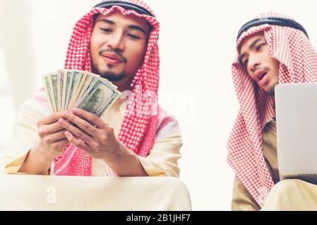 Gutaussehender, gieriger arabischer Mann, der Geld auf den Händen zeigt und Geld auszählt. Konzept der Finanzbeschädigung. Stockfoto