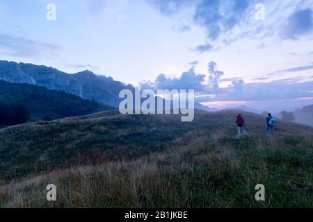 Zwei Wanderer gehen in Campogrosso vorbei. Im Hintergrund Mount La Sisilla. Piccole Dolmiti, Provinz Vicenza, Venetien, Italien, Europa. Stockfoto