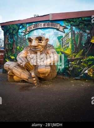 Berühmte Holz-Troll-Skulptur in Christjana freetown in Kopenhagen mit Wandbild im Hintergrund. Tagesschuss am bewölkten Tag, keine Menschen. Stockfoto