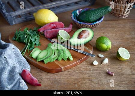 Kochen mexikanische Guacamole - Avocado, Limette, Zitrone, Pfeffer, Knoblauch und Koriander auf einer hölzernen Tisch. essen Hintergrund mit Kopie Raum Stockfoto