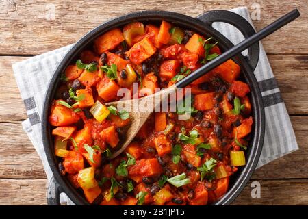 Chili Süßkartoffeln und schwarze Bohnen mit Tomaten, Sellerie in einer Pfanne auf dem Tisch. Horizontale Draufsicht von oben Stockfoto